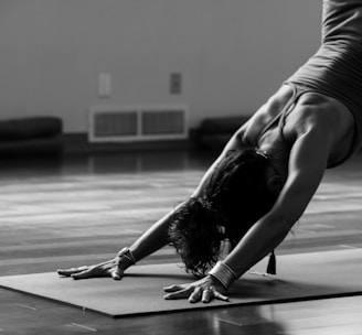 woman in black tank top and black pants bending her body on floor