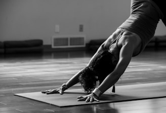 woman in black tank top and black pants bending her body on floor