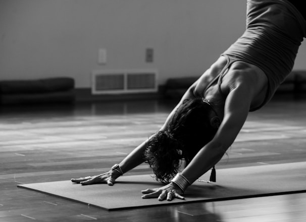 woman in black tank top and black pants bending her body on floor