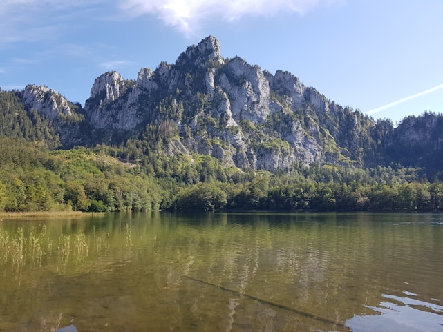 A serene landscape with a calm lake reflecting mountains under a clear sky.