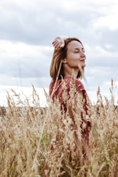 woman in red and white floral dress standing on brown grass field during daytime
