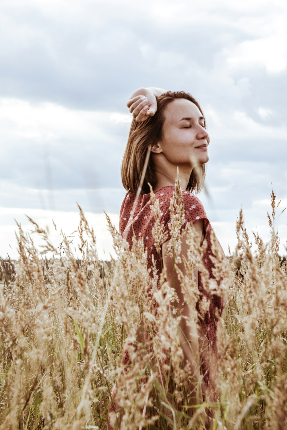 woman in red and white floral dress standing on brown grass field during daytime