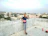 Happy young woman holding keys to her new Sai Skyline Infra apartment with Udaipur cityscape behind.