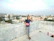 Happy young woman holding keys to her new Sai Skyline Infra apartment with Udaipur cityscape behind.