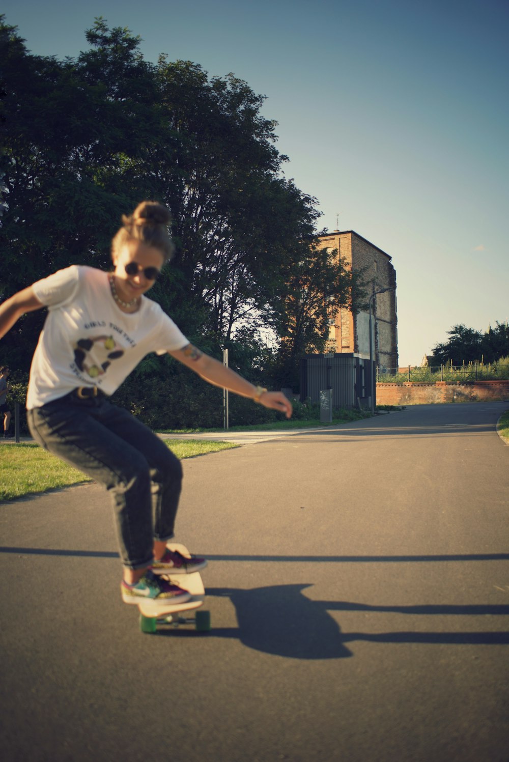 girl in white shirt and black pants riding skateboard during daytime