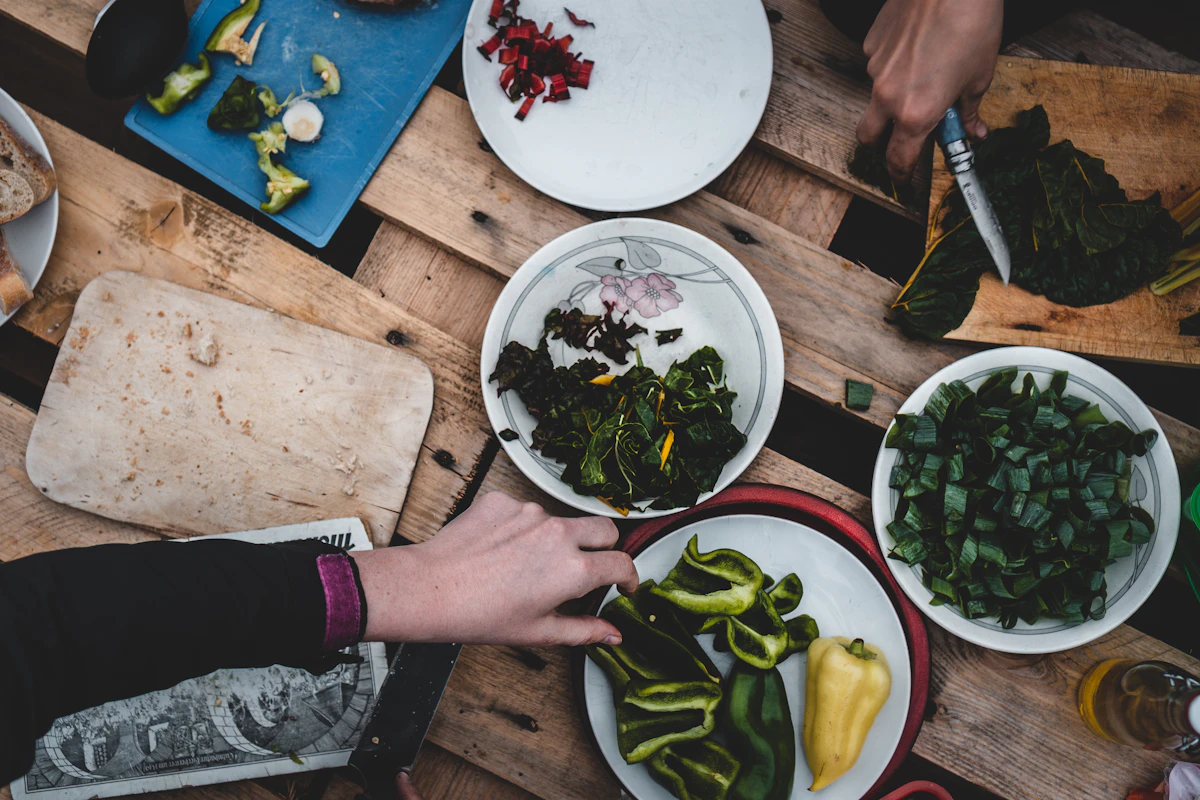 Friends preparing a fresh meal of greens, avocado and peppers together