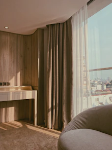 A cozy corner featuring a minimalist dressing table with a soft cushioned stool and natural sunlight streaming in.