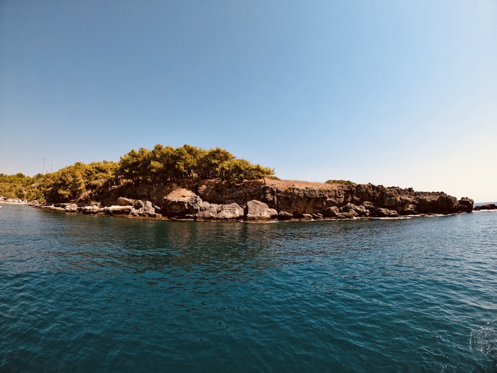 brown and green rock formation on blue sea under blue sky during daytime