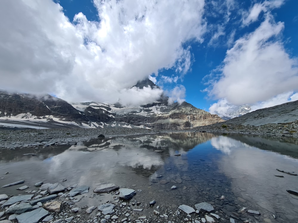 lake in the middle of mountains under white clouds and blue sky during daytime