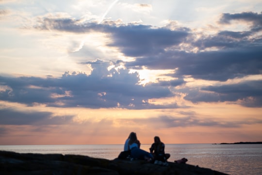 silhouette of man and woman sitting on rock near sea during sunset in Varberg Sweden