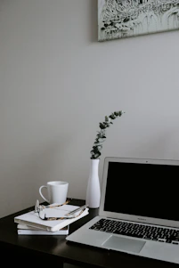 A minimalist workspace with academic books and a laptop displaying a research article on international relations.