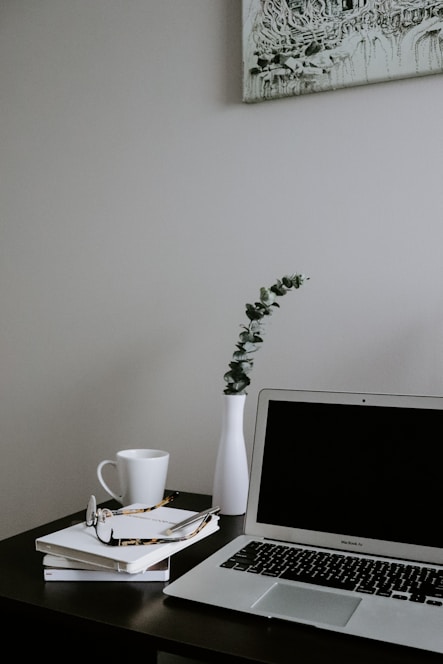 Minimalist modern workspace with laptop, notebook, and coffee cup in soft blue and gray tones.