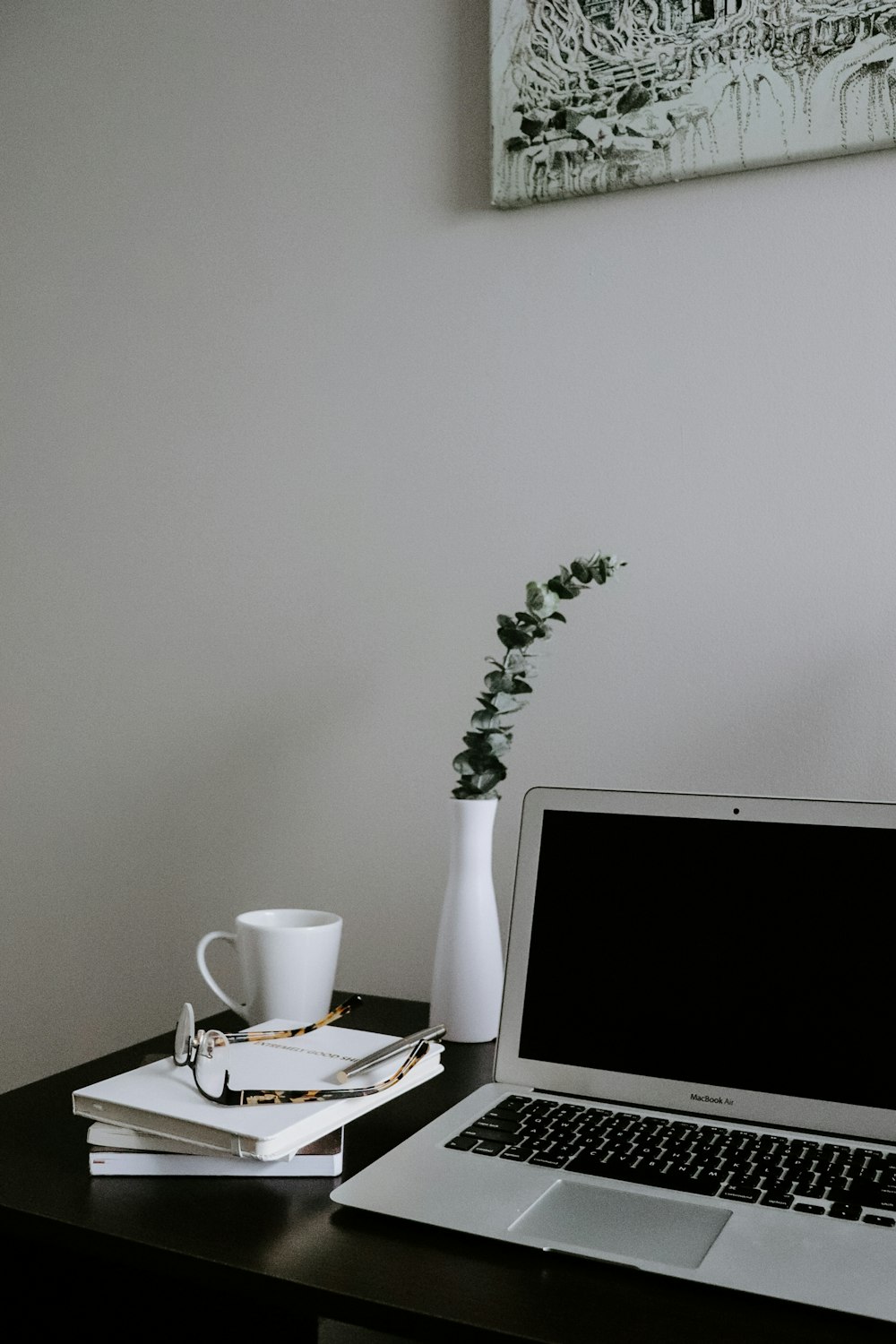 Tasse en céramique blanche sur soucoupe en céramique blanche à côté du MacBook argenté