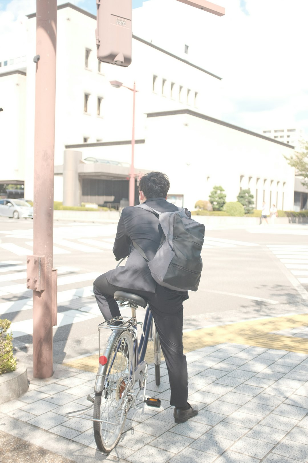 man in black suit riding on bicycle during daytime