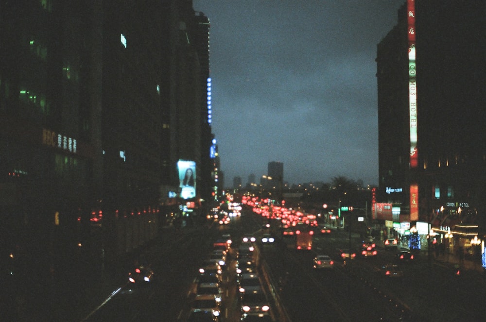 cars on road between high rise buildings during night time