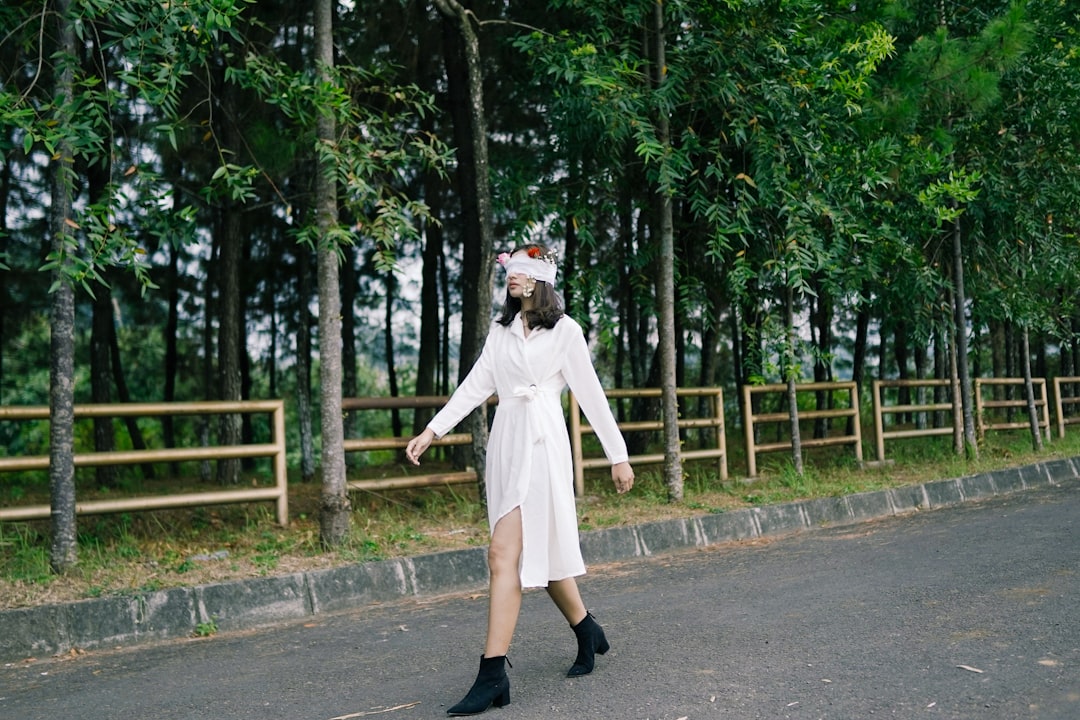 woman in white coat and black skirt standing on road during daytime