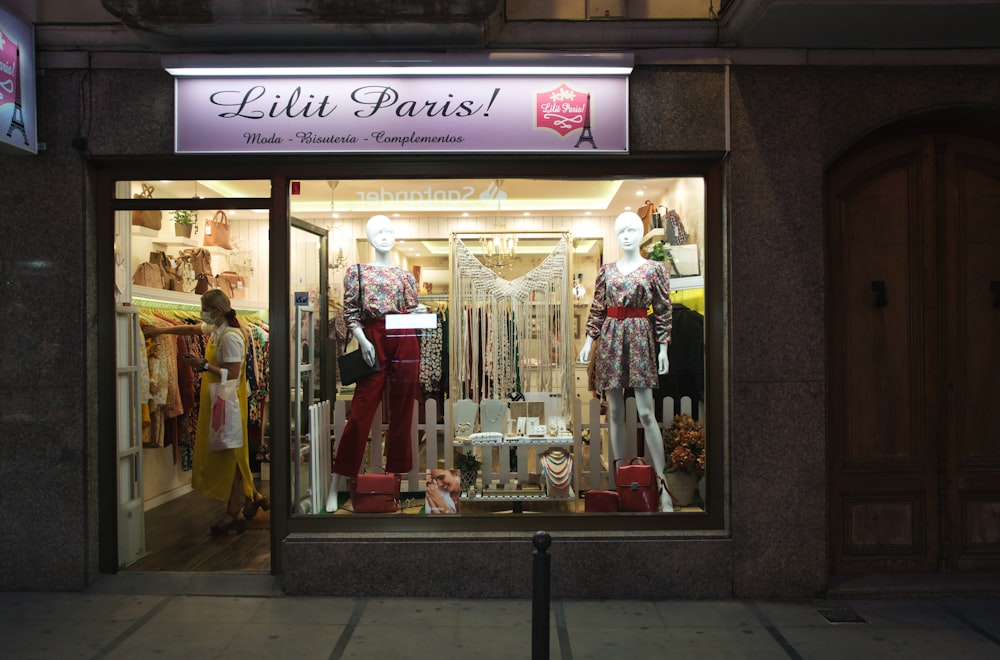 woman in red dress standing in front of store