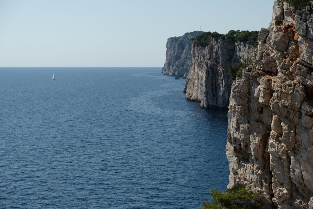 brown rocky mountain beside blue sea during daytime