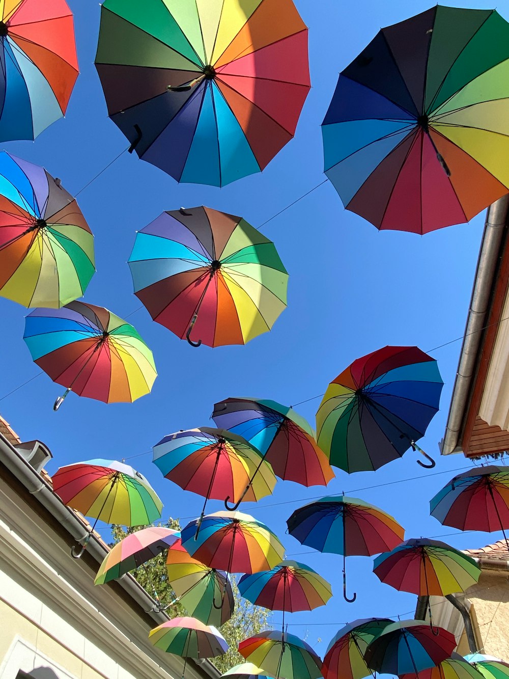 multi colored umbrella hanging on brown wooden pole during daytime