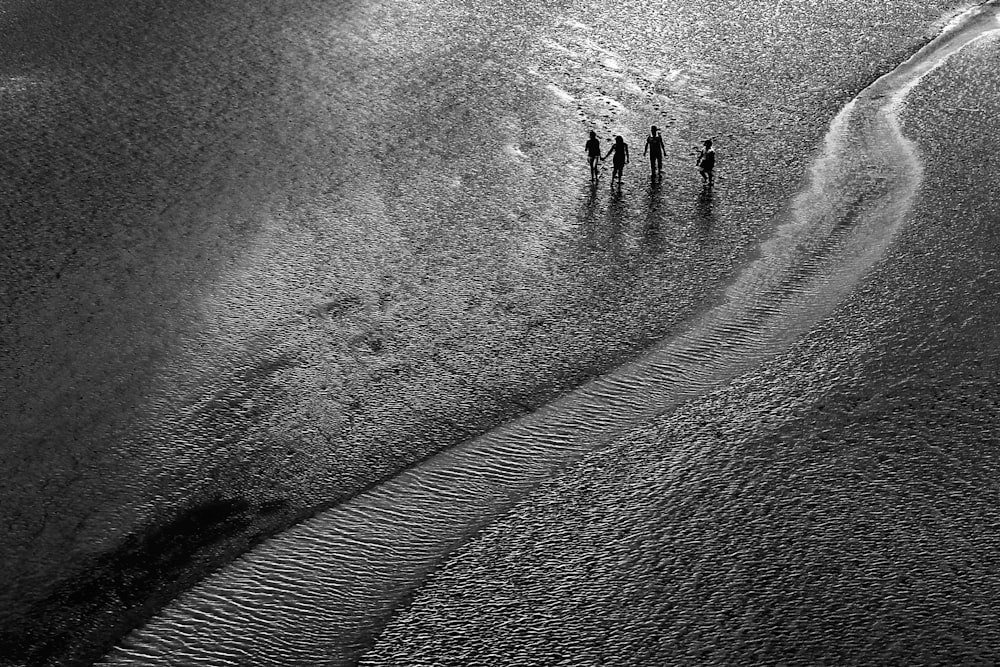 grayscale photo of people walking on sand