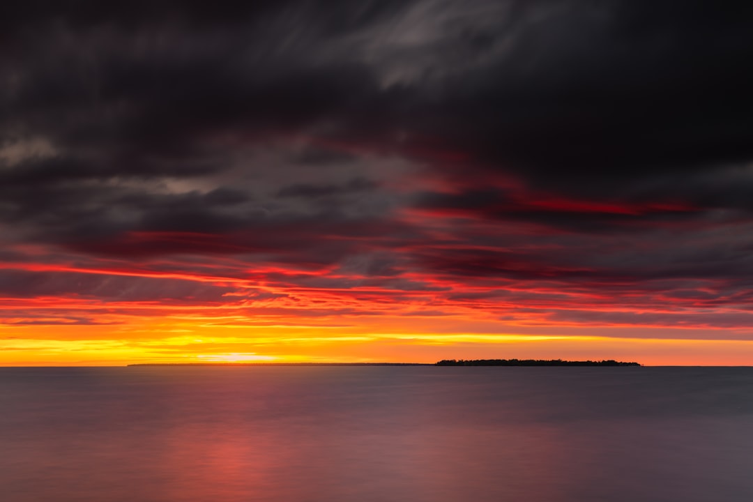 body of water under cloudy sky during sunset