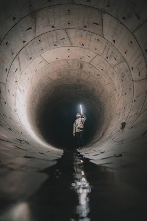 Team member inspecting a cleared main sewage pipe with a flashlight.