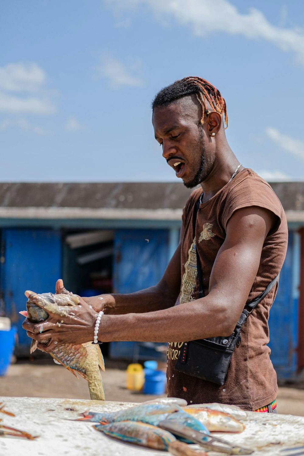 man in brown tank top holding white and blue textile during daytime