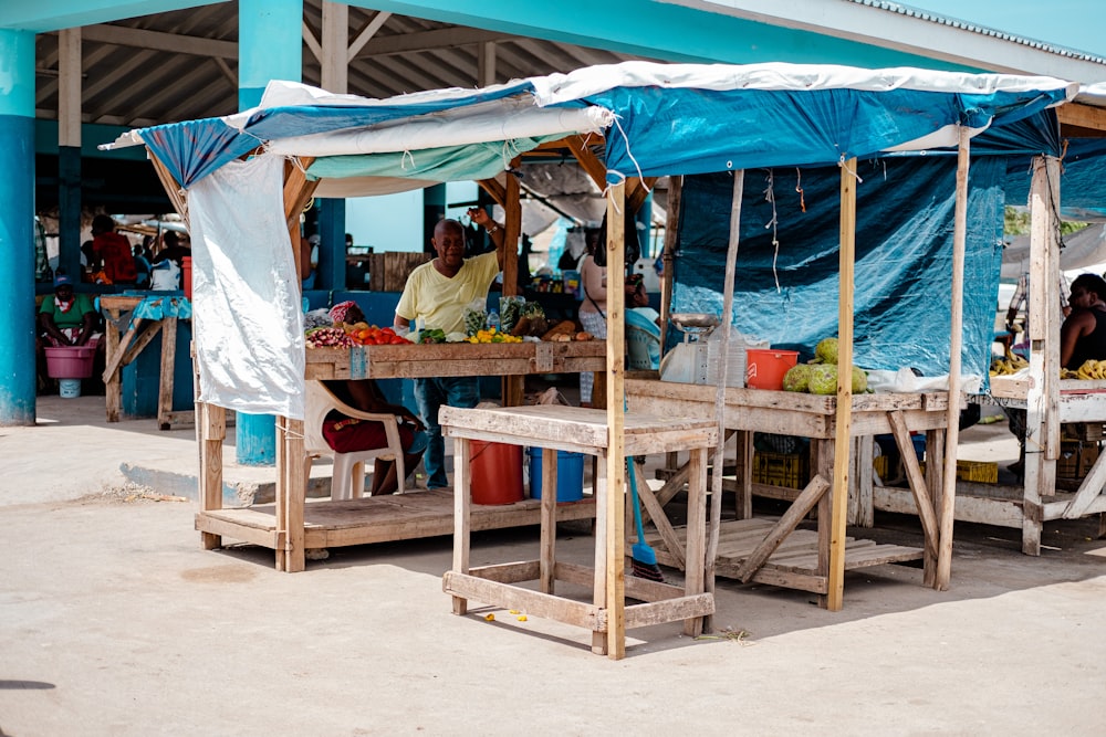 people sitting on brown wooden picnic table under blue and white canopy tent during daytime