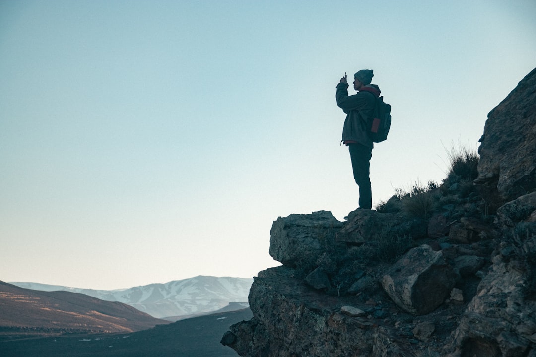 man in black jacket standing on rock formation during daytime