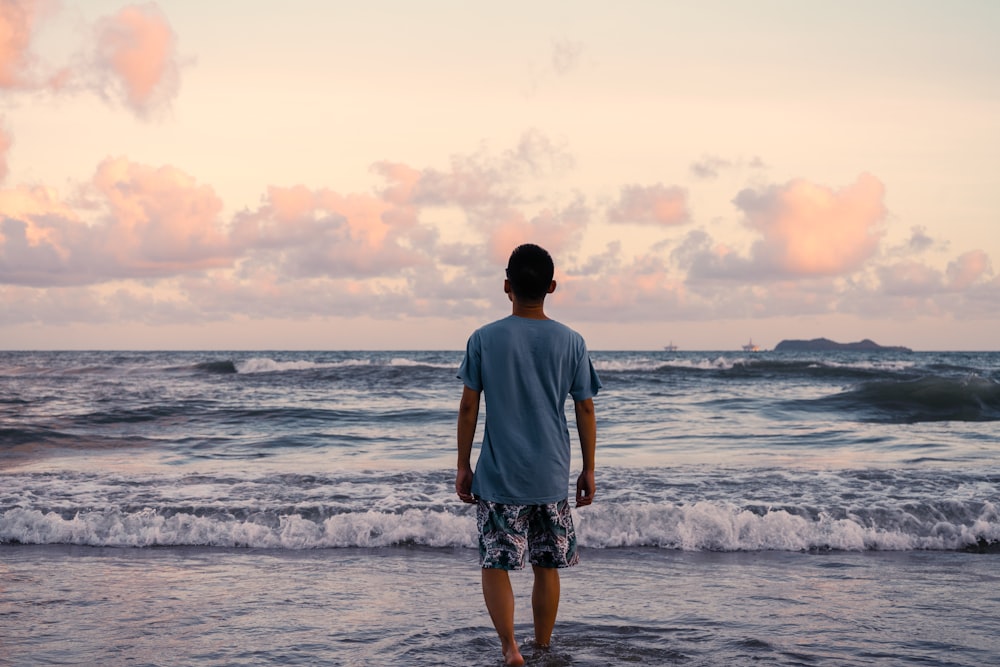 man in gray t-shirt standing on seashore during daytime