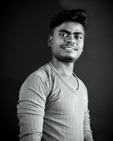 A stylish young man in a modern black shirt posing against a minimalist white background.