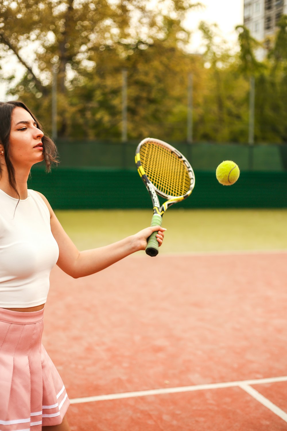 woman in white tank top and pink shorts holding tennis racket