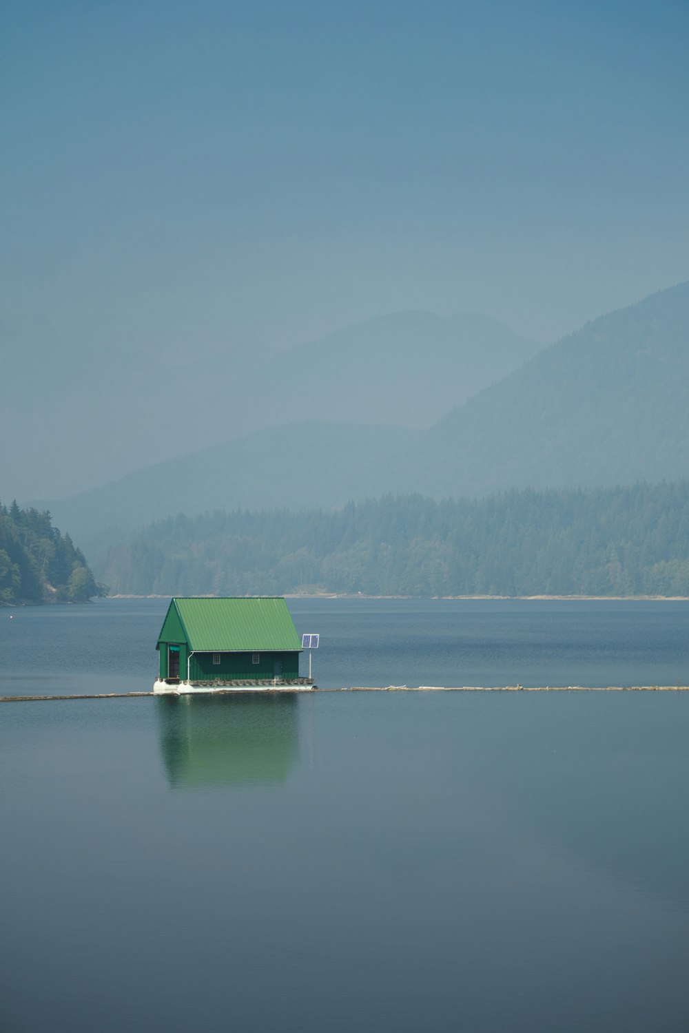 낮 동안 호수에 있는 녹색과 흰색 집