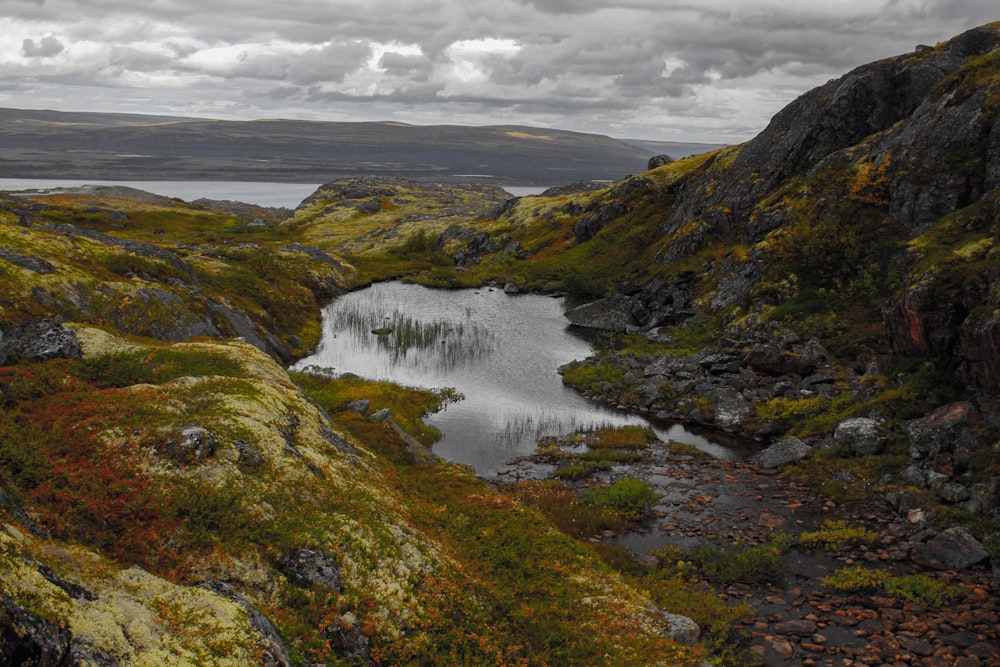 green and brown mountain beside lake under white clouds during daytime