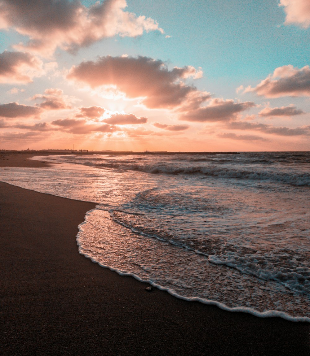 sea waves crashing on shore during sunset