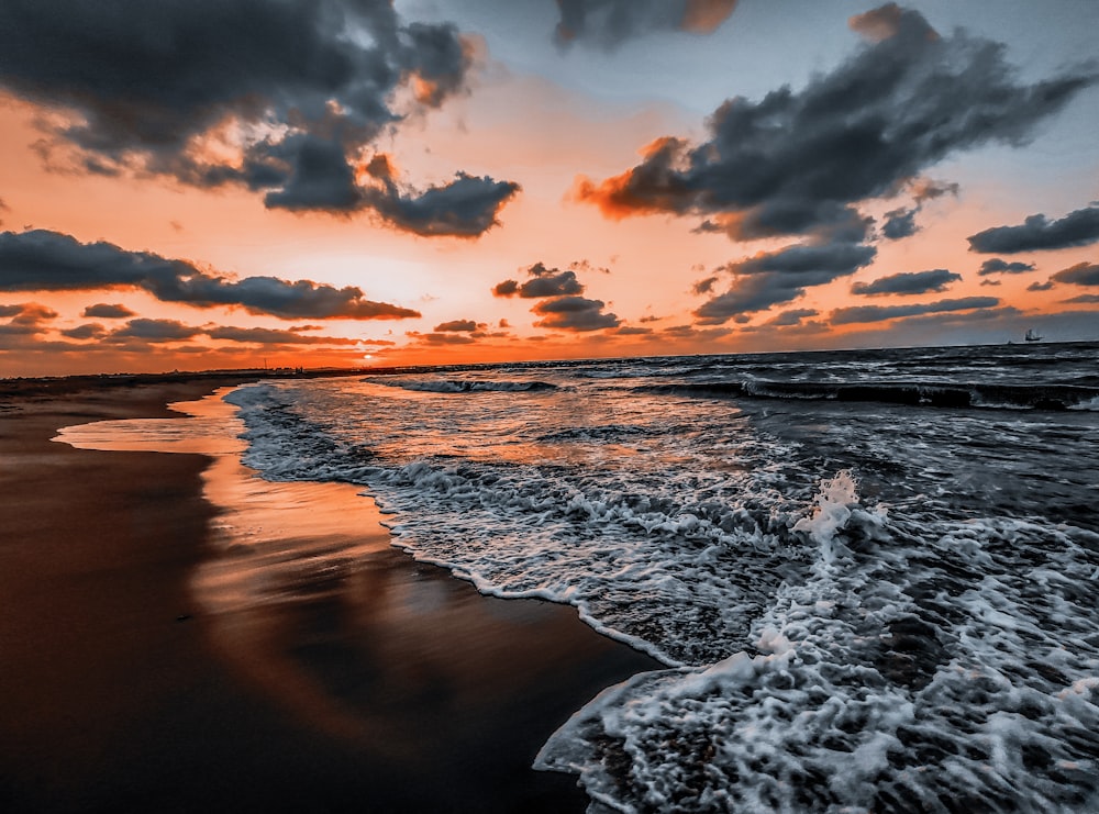 ocean waves crashing on shore during sunset