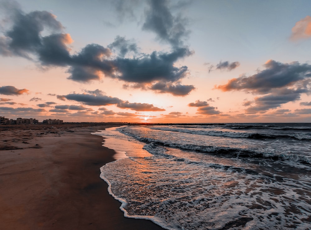 sea waves crashing on shore during sunset