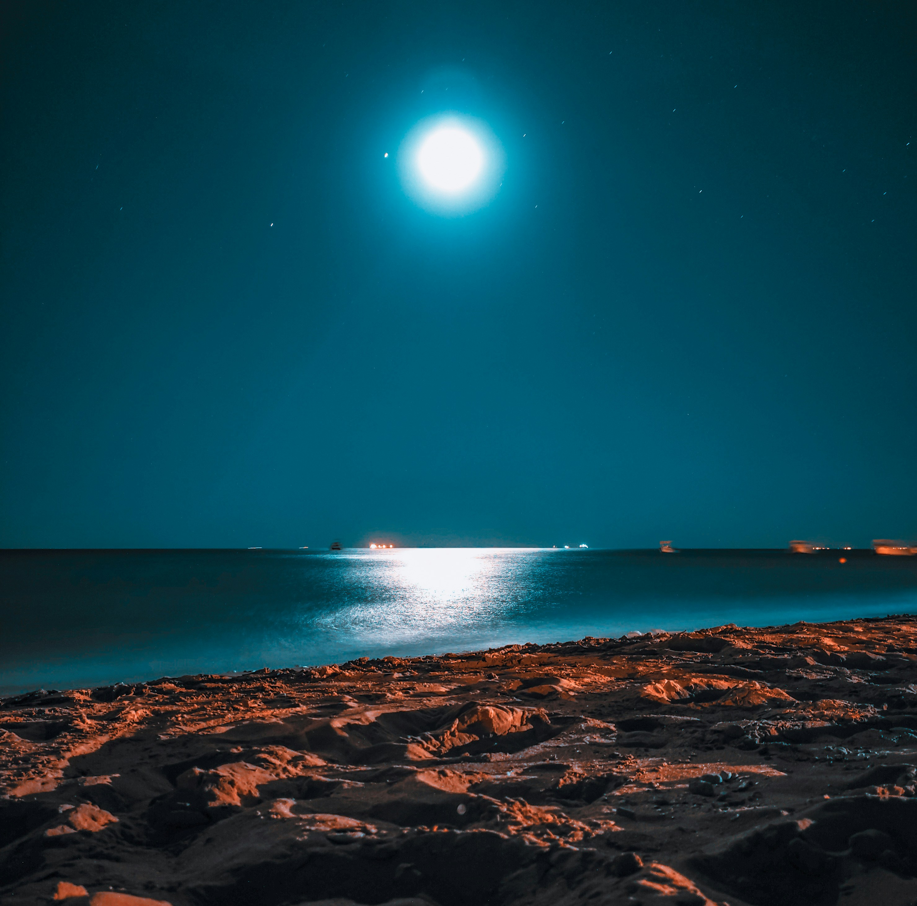 arena marrón cerca del cuerpo de agua durante la noche