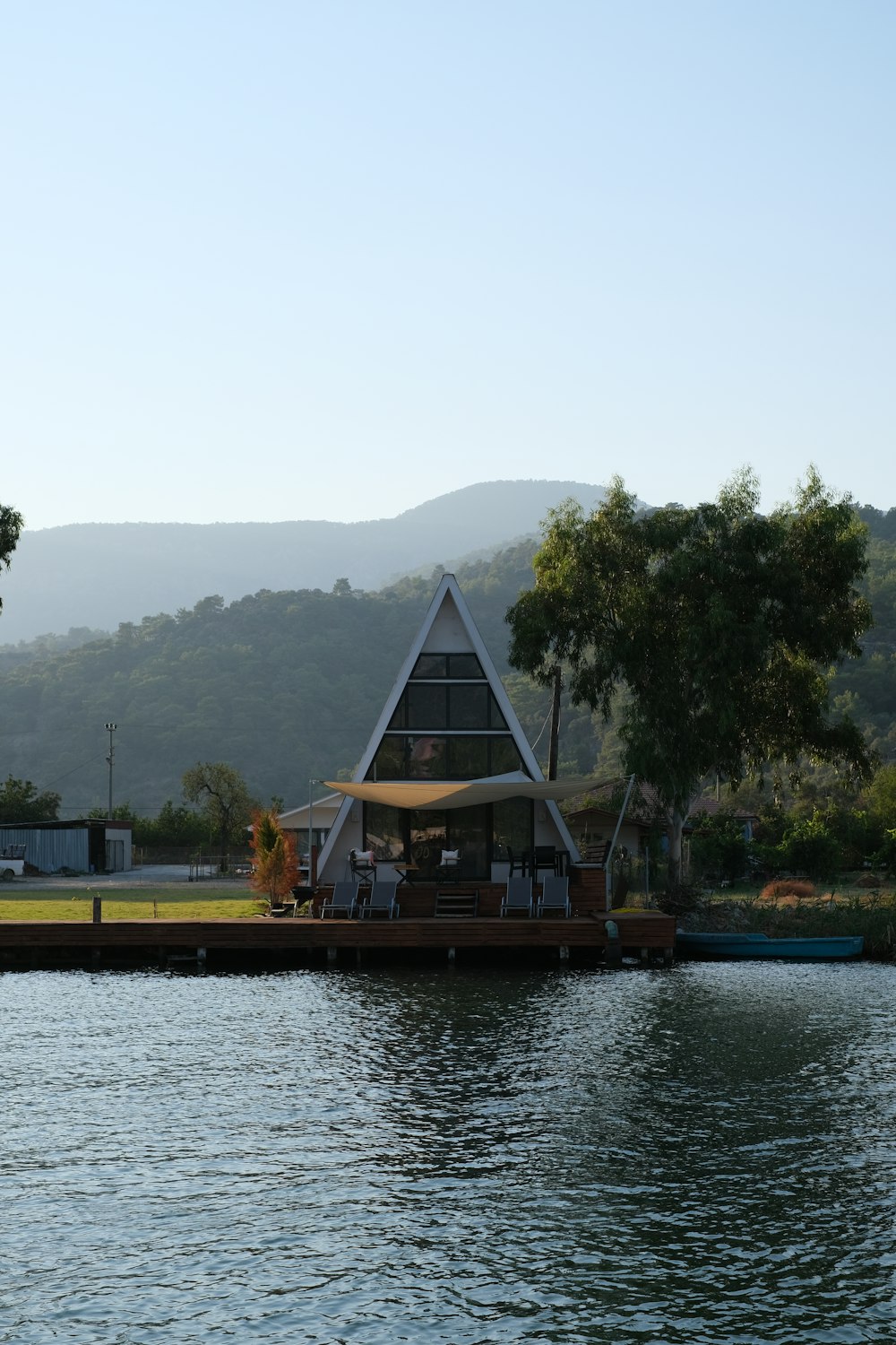 brown wooden house near green trees and body of water during daytime