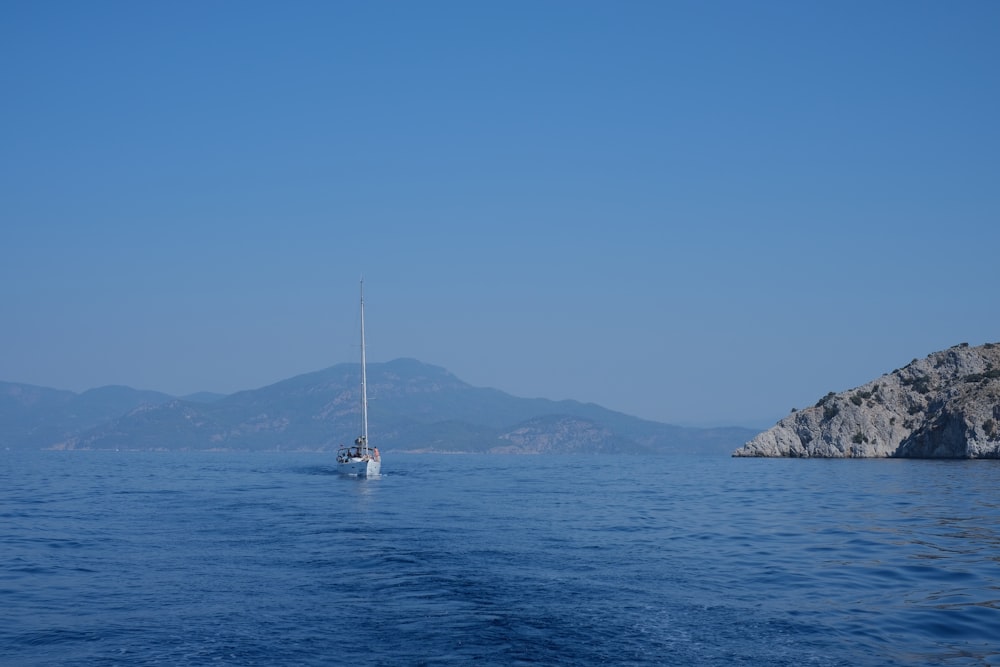 white sailboat on sea near mountain during daytime