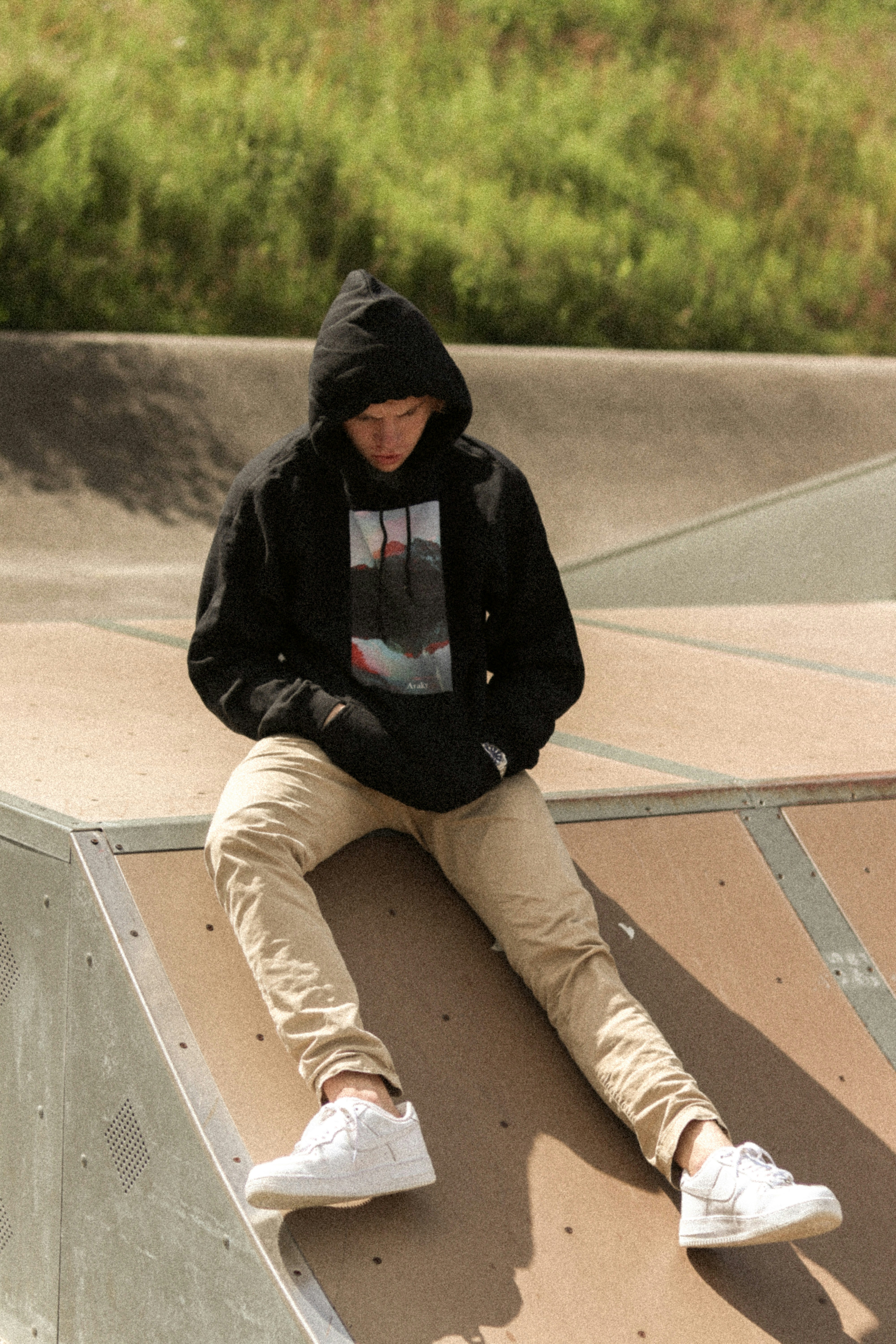 Woman in black hoodie and brown pants sitting on white concrete bench ...