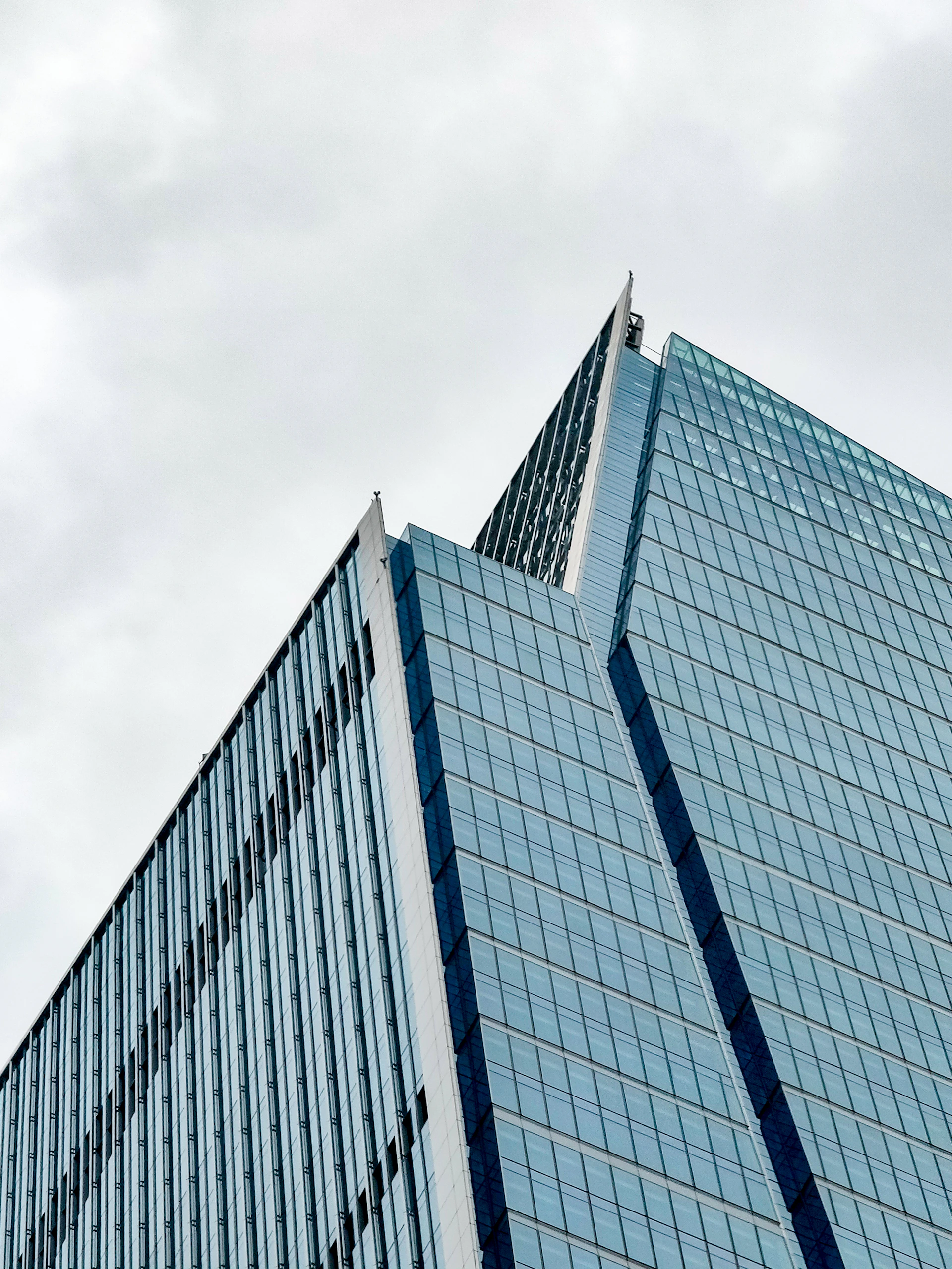 A striking urban office building with sharp angles and a mix of concrete and steel materials, set against a city skyline.