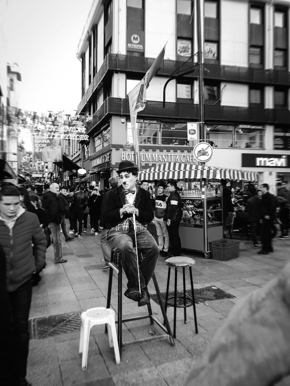 grayscale photo of man in black jacket sitting on chair