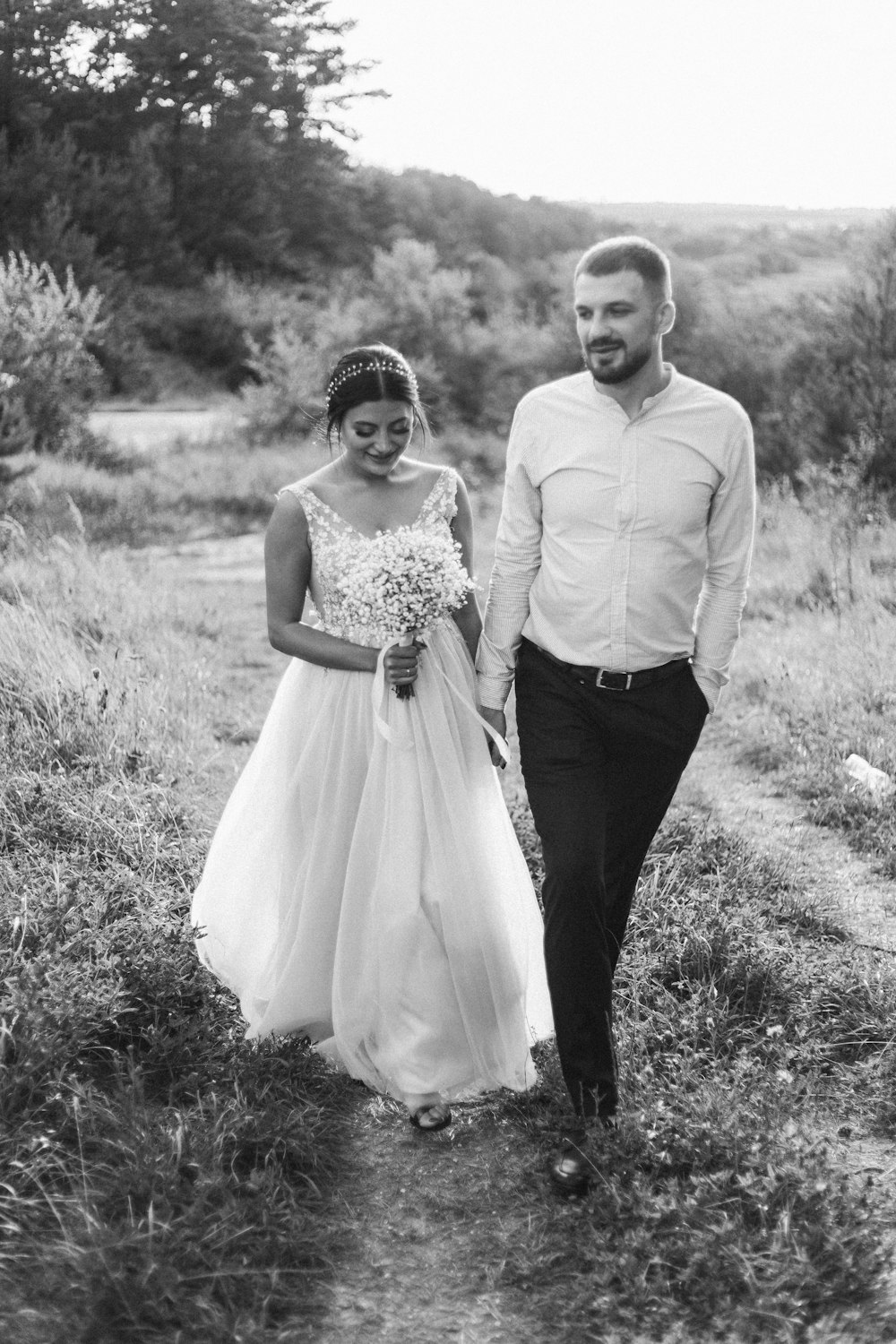 grayscale photo of man and woman standing on grass field