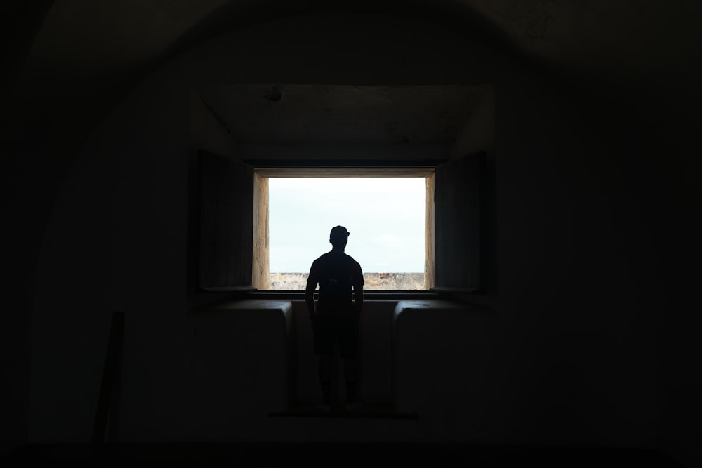 silhueta do homem em pé na frente da janela