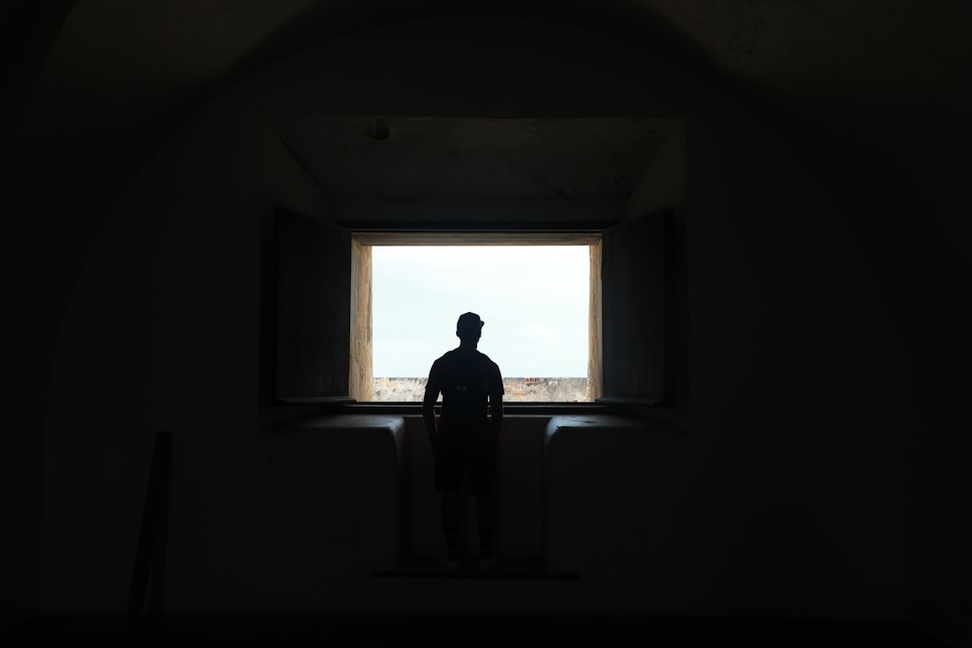 silhouette of man standing in front of window