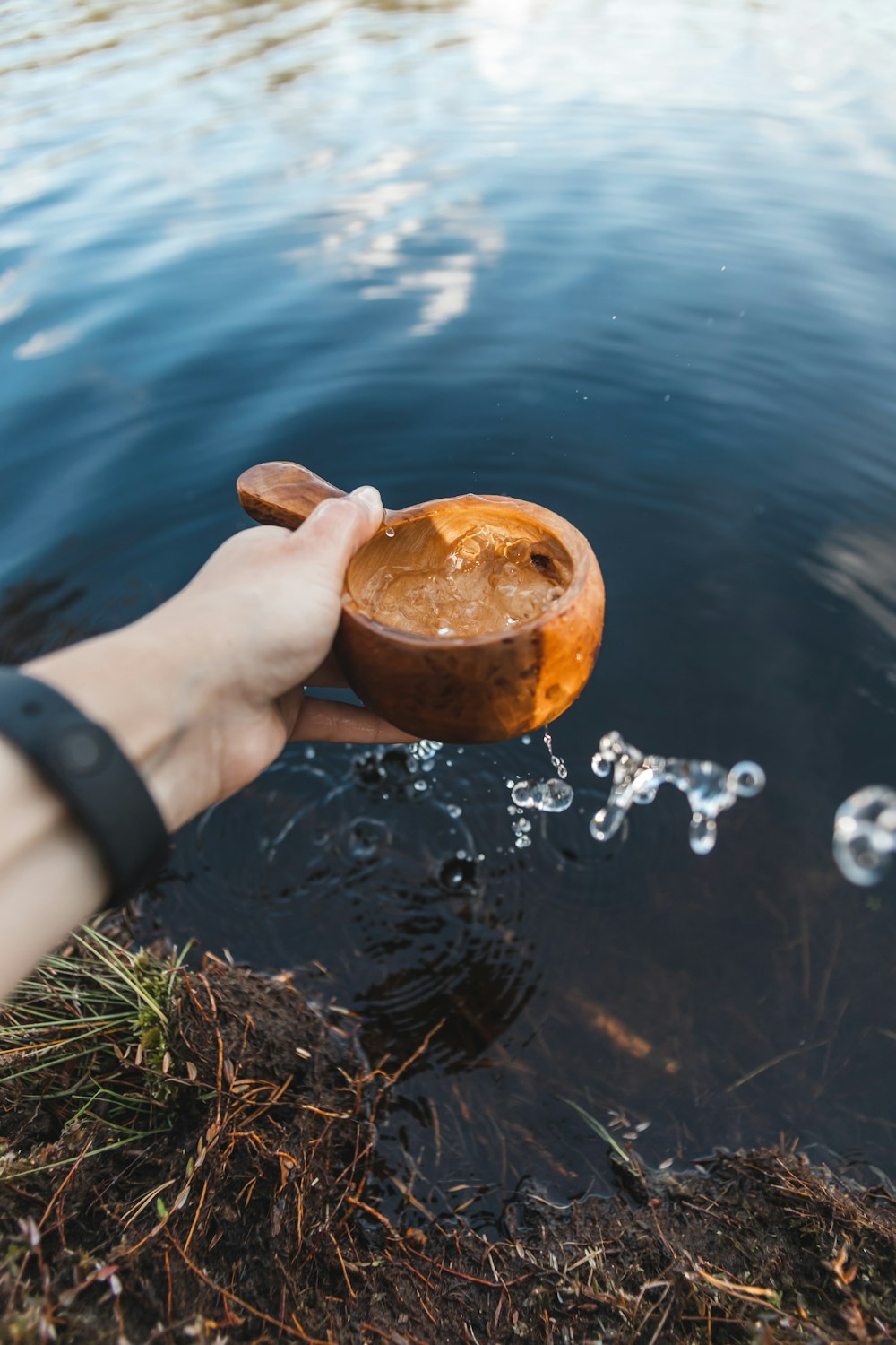 person holding brown wooden round container