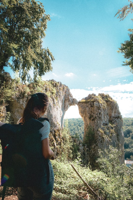 woman in white t-shirt sitting on rock formation during daytime in Blaubeuren Germany