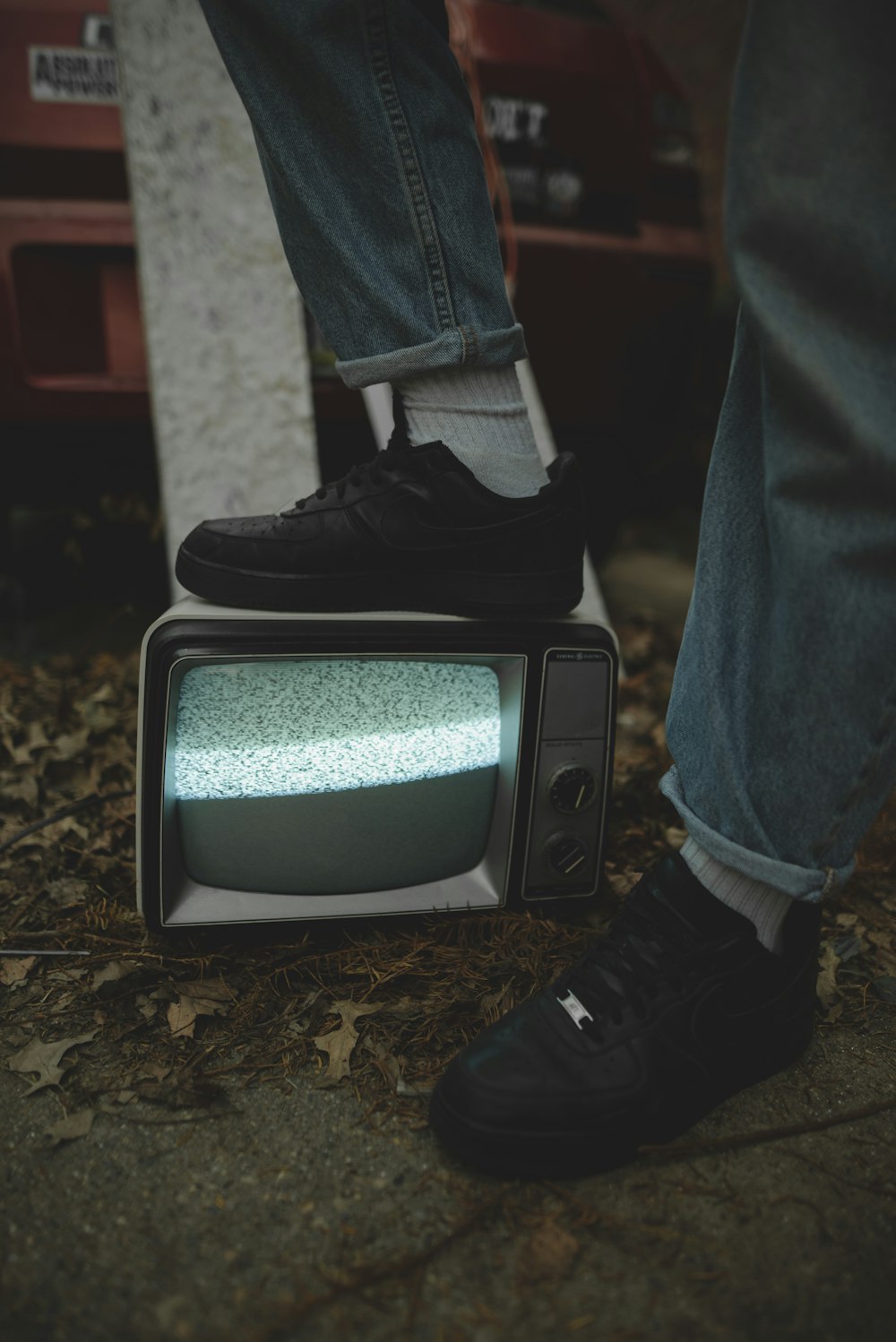 person in blue denim jeans and black nike shoes standing on brown soil