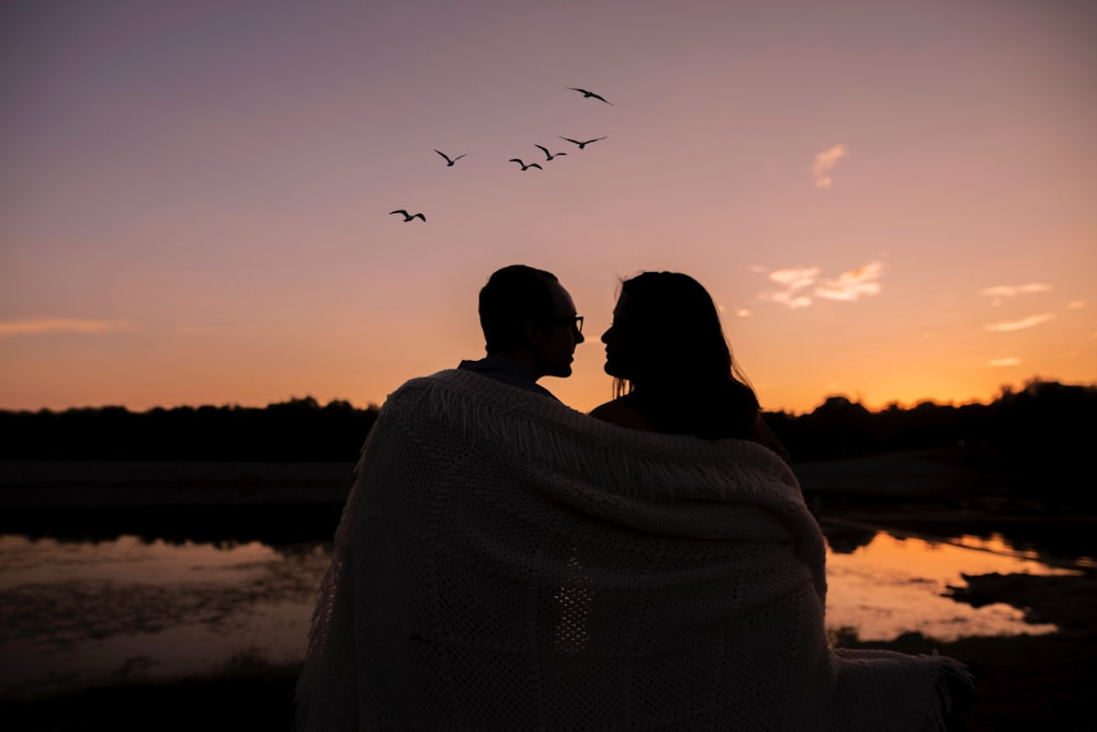 woman in white knit sweater looking at birds flying during sunset